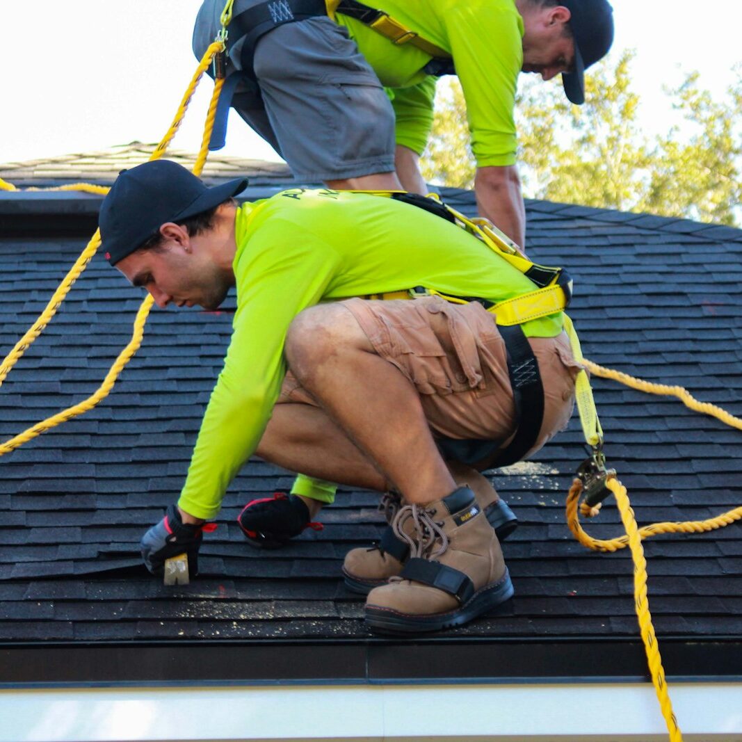 two men working on the roof of a house